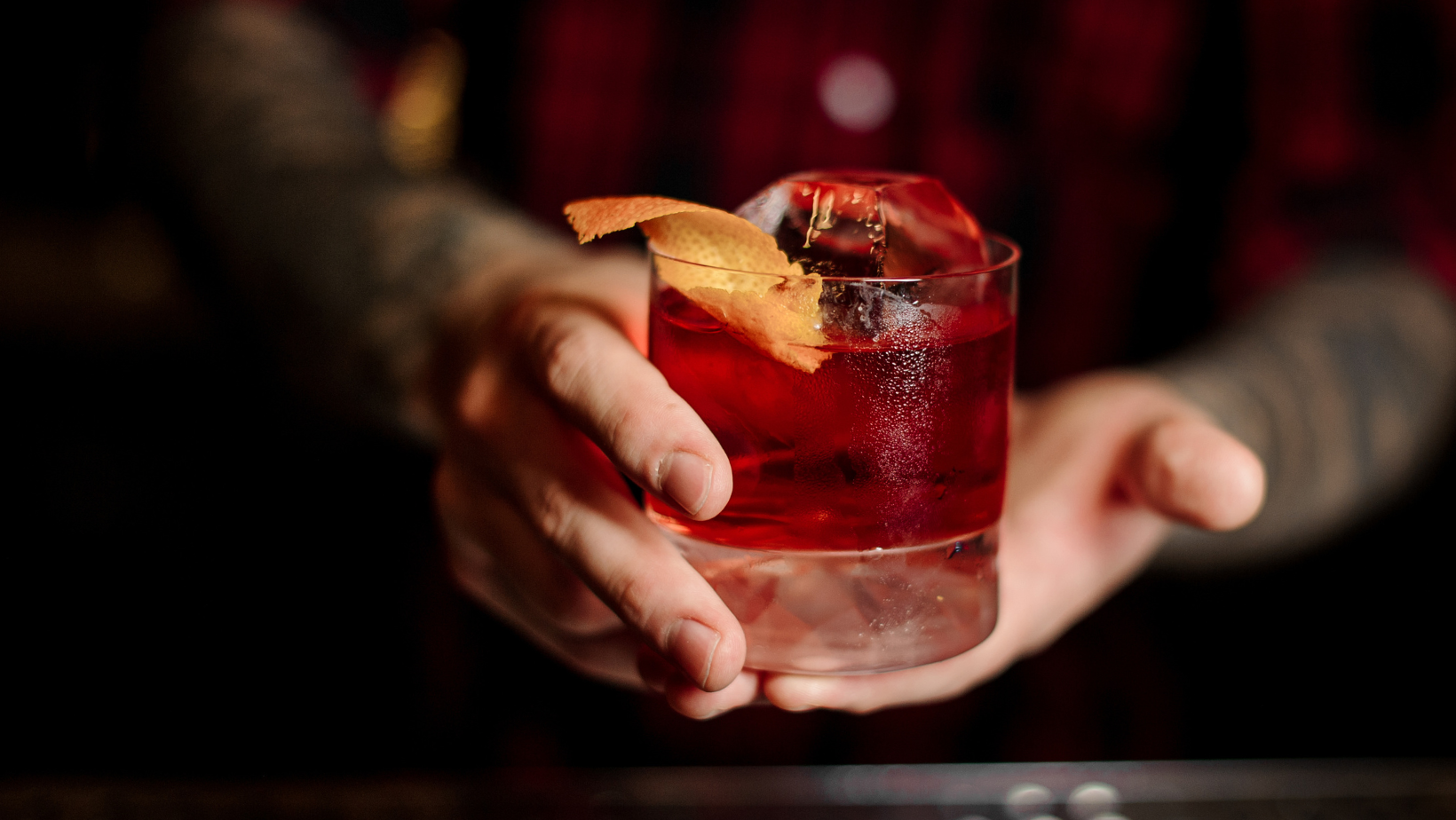 A bartender gently presenting a freshly made cocktail to you.